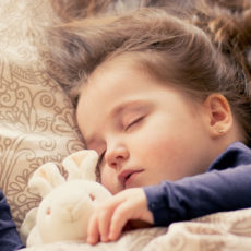 Ein kleines Mädchen schläft entspannt mit ihrem Kuscheltier