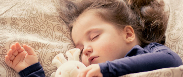 Ein kleines Mädchen schläft entspannt mit ihrem Kuscheltier